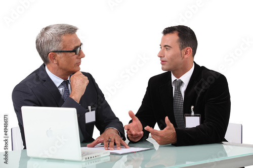 Photo: Men chatting at a desk Men chatting at a desk