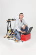 Carpenter kneeling by laptop