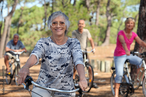 Photo: old woman and three other people doing bike in the forest old woman and three other people doing bike in the forest