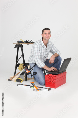 Photo: Carpenter kneeling by laptop Carpenter kneeling by laptop