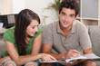 young couple at home skimming through catalogue