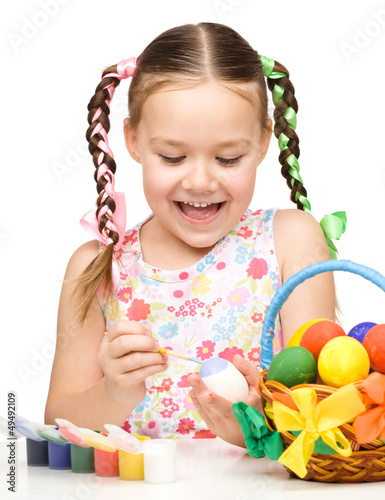 Photo: Little girl is painting eggs preparing for Easter Little girl is painting eggs preparing for Easter
