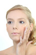 Young blond woman applying beauty cream