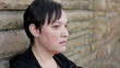 Sad woman sitting against a wall close up