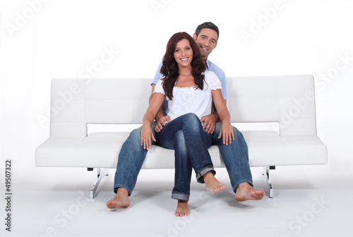 Photo: Happy couple on a sofa, studio shot Happy couple on a sofa, studio shot