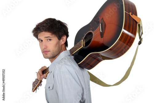 Photo: young man carrying a guitar on his shoulder young man carrying a guitar on his shoulder