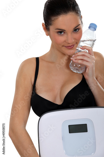 Photo: Young woman carrying scales and bottle of water Young woman carrying scales and bottle of water