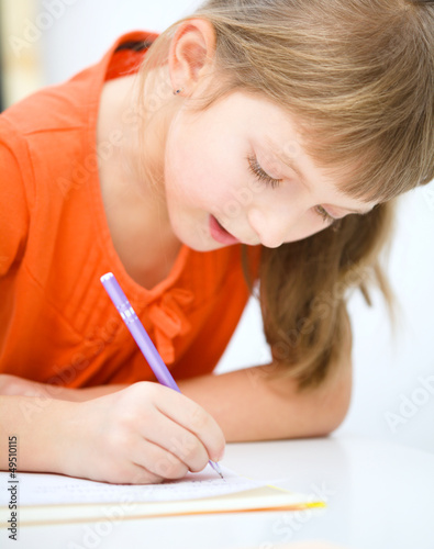 Photo: Little girl is writing using a pen Little girl is writing using a pen