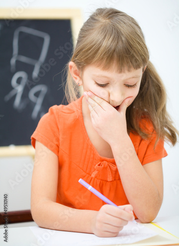 Photo: Little girl is writing using a pen Little girl is writing using a pen