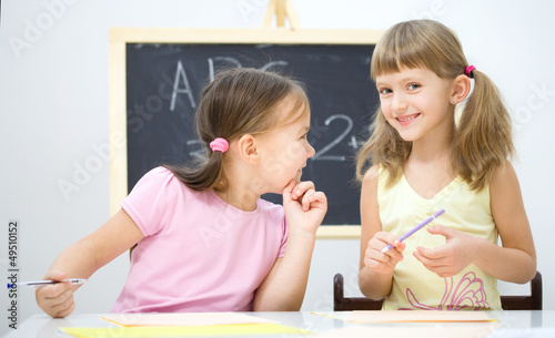 Photo: Little girls are writing using a pen Little girls are writing using a pen