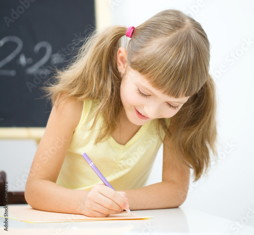Photo: Little girl is writing using a pen Little girl is writing using a pen