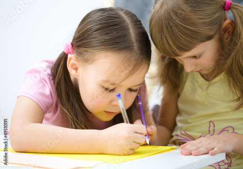 Photo: Little girls are writing using a pen Little girls are writing using a pen