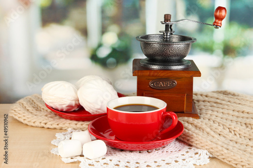 Photo: cup of coffee with scarf and coffee mill on table in room cup of coffee with scarf and coffee mill on table in room