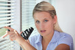 Woman peering through blinds with binoculars