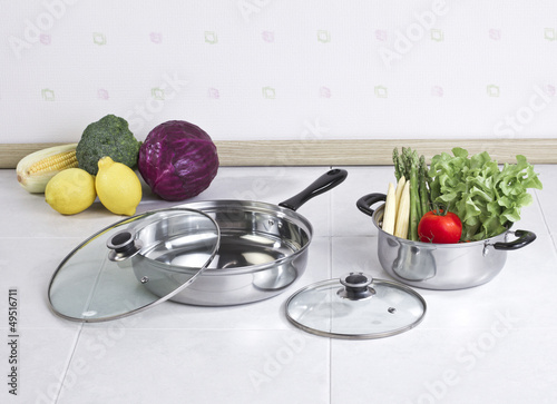 Photo: Set of stainless pot and pan with glass lids and vegetables Set of stainless pot and pan with glass lids and vegetables