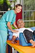 Mann bei Krankengymnastik neben Physiotherapeutin