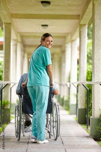 Photo: Krankenpflegerin schiebt Mann im Rollstuhl Krankenpflegerin schiebt Mann im Rollstuhl