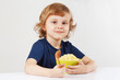 Little blonde boy hugging a green bowl of millet porridge