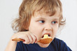 Little cute child bites millet cereal from a spoon
