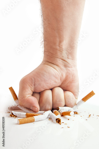 Photo: Human fist breaking cigarettes on white background Human fist breaking cigarettes on white background