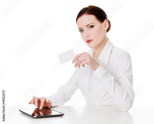 Photo: Woman sitting with a tablet computer and holding a credit card Woman sitting with a tablet computer and holding a credit card