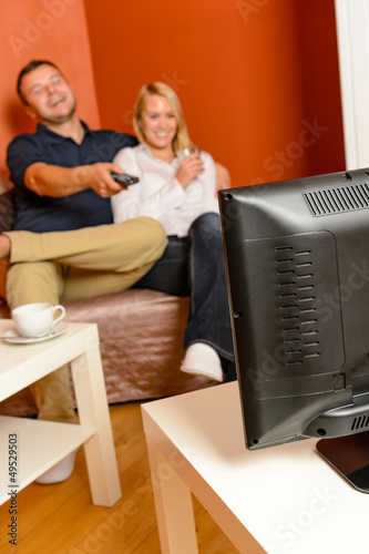 Photo: Happy couple watching television together relaxing sofa Happy couple watching television together relaxing sofa