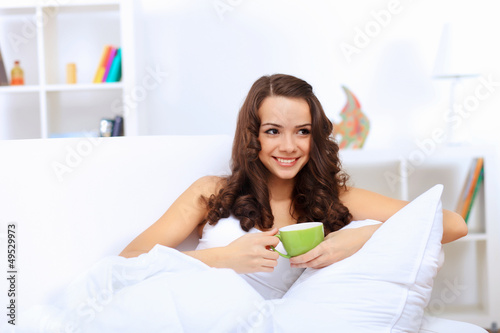 Photo: Young woman having cup of tea at home Young woman having cup of tea at home