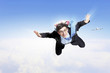 Young businessman flying with parachute on back