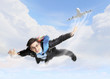 Young businessman flying with parachute on back