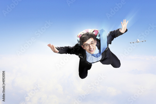 Photo: Young businessman flying with parachute on back Young businessman flying with parachute on back