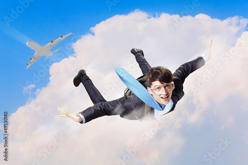Photo: Young businessman flying with parachute on back Young businessman flying with parachute on back