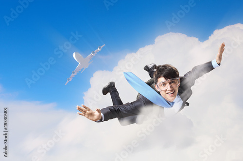 Photo: Young businessman flying with parachute on back Young businessman flying with parachute on back