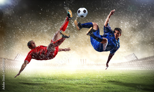 Photo: two football players striking the ball two football players striking the ball