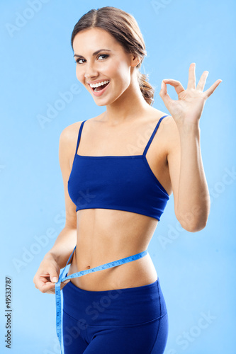 Photo: Woman in fitness wear with tape, over blue Woman in fitness wear with tape, over blue