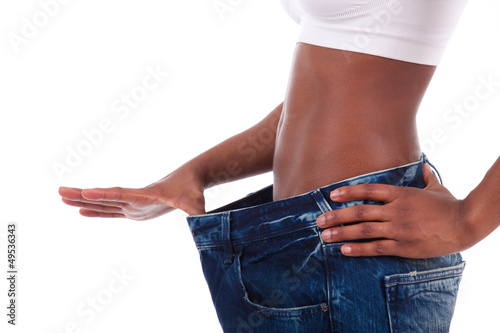 Photo: Young african woman in old jeans pant after losing weight Young african woman in old jeans pant after losing weight