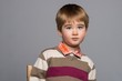 Little boy in cardigan sitting on chair