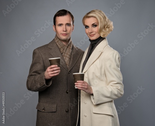 Photo: Elegant couple with cups isolated on grey Elegant couple with cups isolated on grey