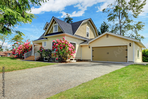 Photo: Yellow house exterior with spring blooming rhododendron Yellow house exterior with spring blooming rhododendron