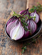 Halved red onions with thyme on a ceramic plate