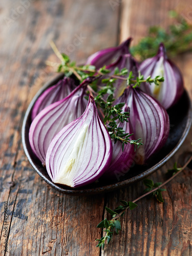 Photo: Halved red onions with thyme on a ceramic plate Halved red onions with thyme on a ceramic plate