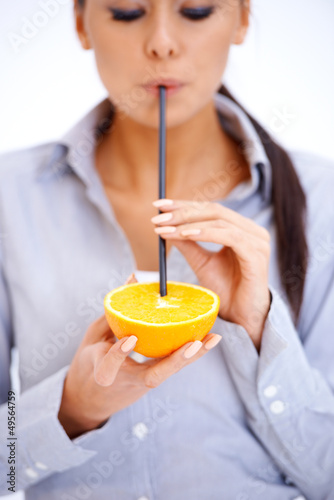 Photo: Woman drinks orange juice through a straw Woman drinks orange juice through a straw