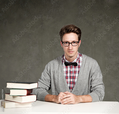 Photo: Student mit Büchern sitzt vor einer Tafel Student mit Büchern sitzt vor einer Tafel