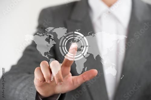 Photo: Business woman pointing her finger on virtual button on world ma Business woman pointing her finger on virtual button on world ma
