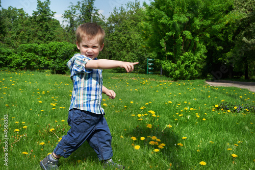 Photo: Little boy goes on meadow and indicates direction Little boy goes on meadow and indicates direction