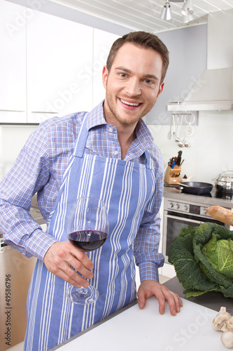 Photo: Lachender Mann in der Küche trinkt Rotwein Lachender Mann in der Küche trinkt Rotwein