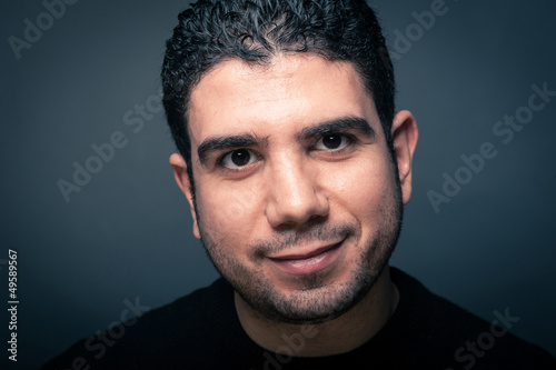 Photo: Happy man close up portrait against dark background. Happy man close up portrait against dark background.