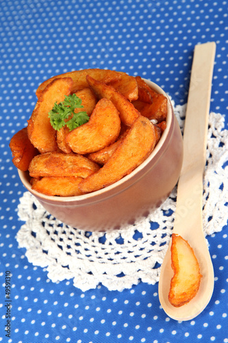 Photo: Appetizing village potatoes in bowl on blue fabric close-up Appetizing village potatoes in bowl on blue fabric close-up