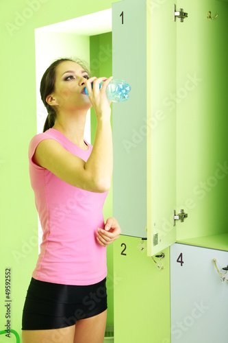 Photo: Young girl in locker room with bottle of water Young girl in locker room with bottle of water
