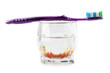 Partial denture inside glass with toothbrush on the top