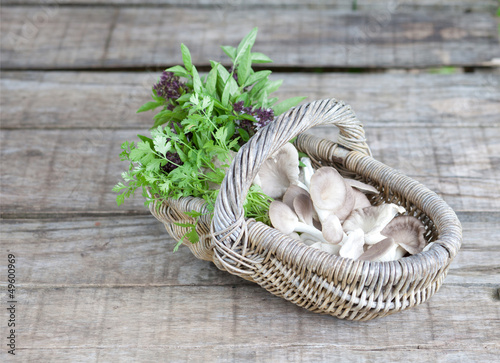Photo: Basket of mushroom, and sweet basil on wooden background Basket of mushroom, and sweet basil on wooden background